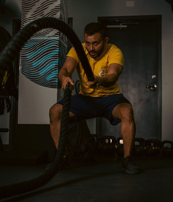 Strong man performing endurance exercises in a dark gym